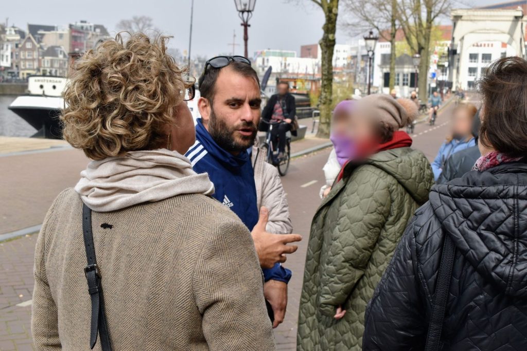 Walking tour group by the Amstel river at the Magere Brug
