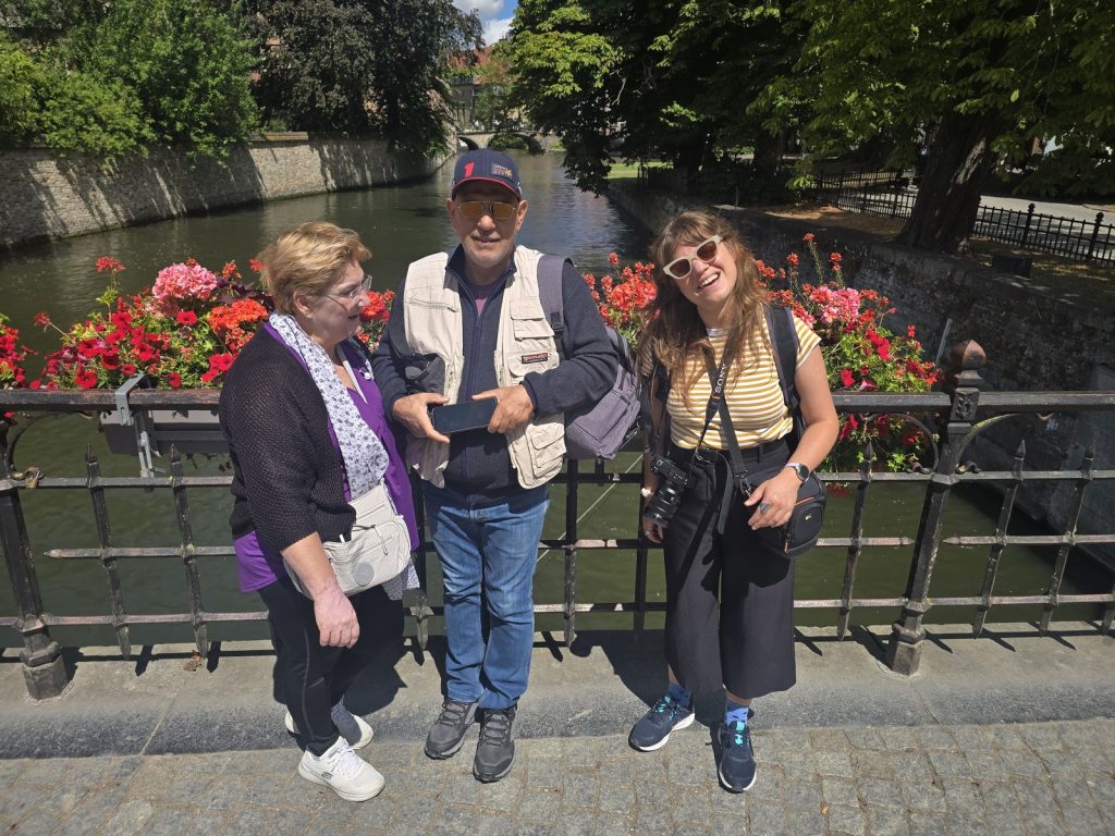 Guests of a private Bruges day trip from Amsterdam standing on a canal bridge with red geraniums