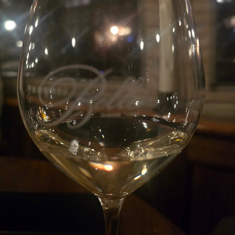 A glass of white wine aboard a canal boat at night, with blurred city lights through the window behind it